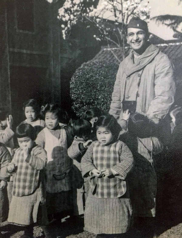 Henry Karanian with a group of children in Shanghai during WWII. Henry served in the US Army Air Force and enjoyed making photographs whenever he could. A child appears to be reaching for his camera.