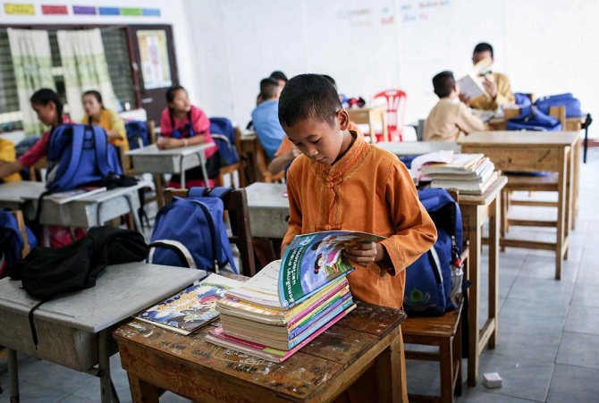 ©UNICEF/Preechapanich - A migrant child looking at books during the class break at the Learning Center at Pa Pao Temple, Thailand