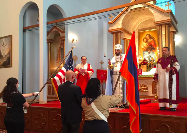 Very Rev. Ghevont Pentezian blesses the Armenian flag as ARF member Dro Grigorian, representing ARF member Yervant Alexanian, serves as godfather of the flag for the ceremony